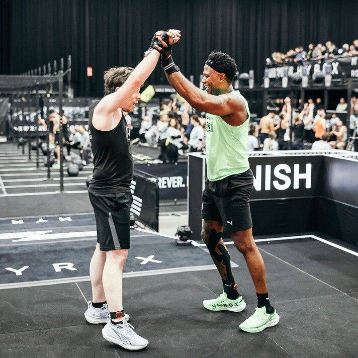 Franklin steekt high-five met een PT-klant na de finish line van een Hyrox-event